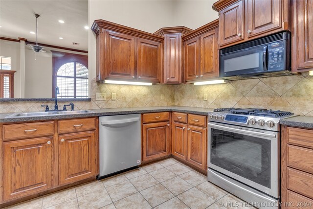 kitchen with light tile flooring, backsplash, ornamental molding, appliances with stainless steel finishes, and sink