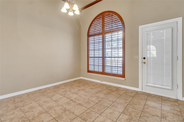 foyer entrance featuring light tile flooring, crown molding, and an inviting chandelier