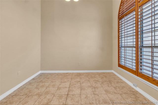 spare room with a wealth of natural light and light tile floors