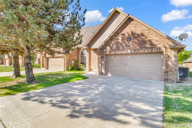 view of front property featuring a front yard, a garage, and central AC unit