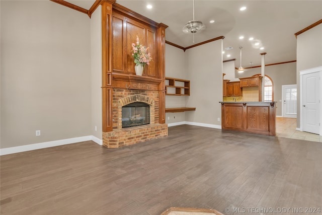 unfurnished living room featuring a fireplace, ceiling fan, light wood-type flooring, and ornamental molding