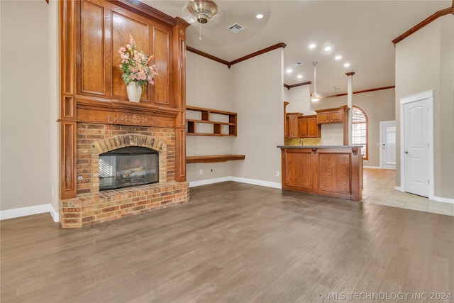 living room with crown molding, light hardwood / wood-style flooring, and a brick fireplace