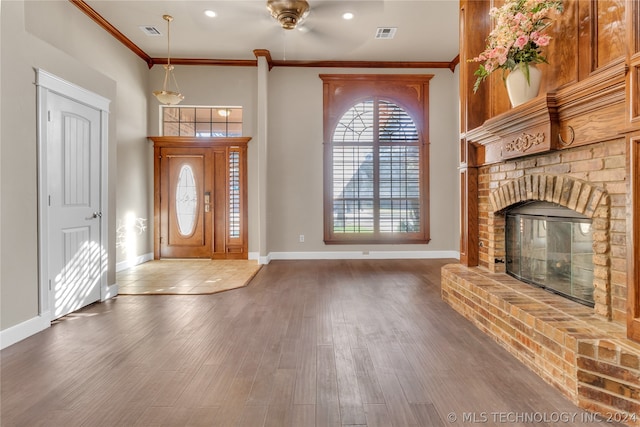 foyer entrance featuring ceiling fan, crown molding, a fireplace, and dark wood-type flooring