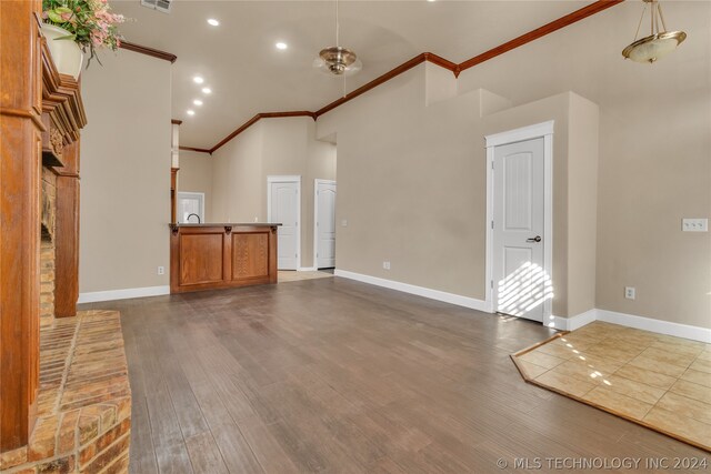 unfurnished living room with ornamental molding, hardwood / wood-style flooring, and high vaulted ceiling