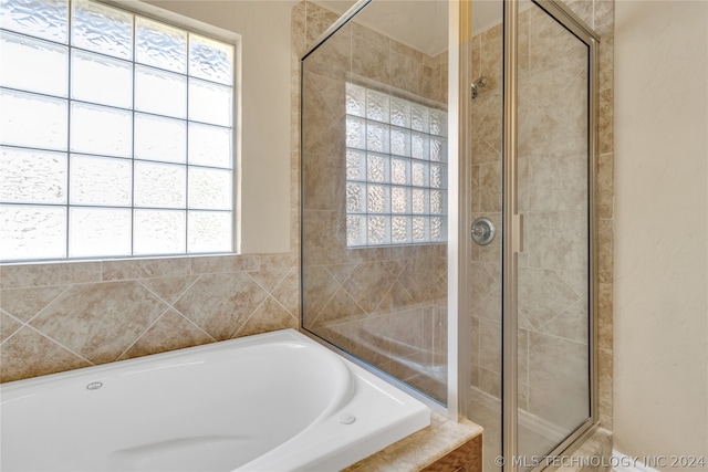 bathroom featuring independent shower and bath and a wealth of natural light