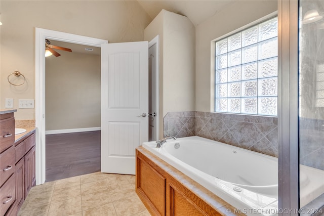 bathroom with tile flooring, ceiling fan, a tub, vaulted ceiling, and vanity