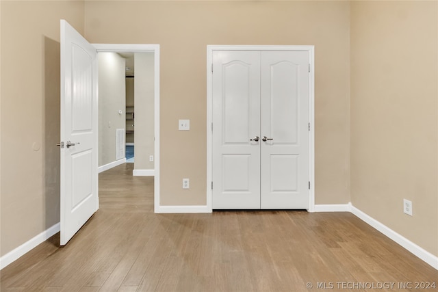 unfurnished bedroom with light hardwood / wood-style flooring and a closet