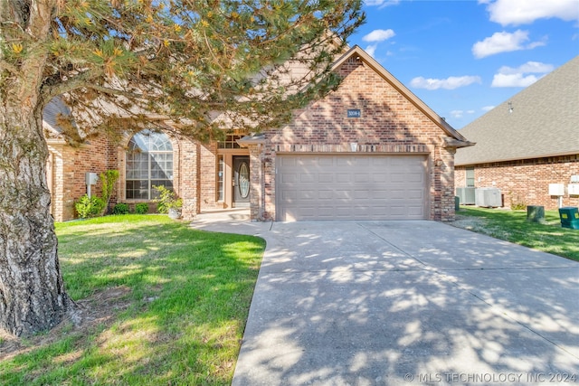 view of front of home featuring a front yard, a garage, and central AC