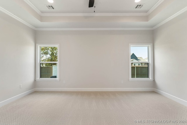 carpeted empty room featuring ceiling fan, ornamental molding, and a tray ceiling