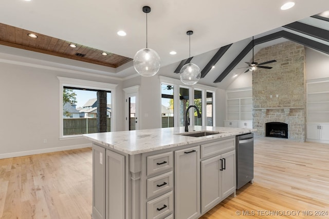 kitchen with an island with sink, vaulted ceiling with beams, light hardwood / wood-style flooring, a fireplace, and sink