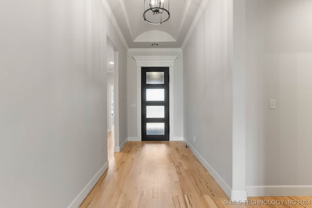 entryway with crown molding, a chandelier, and light wood-type flooring