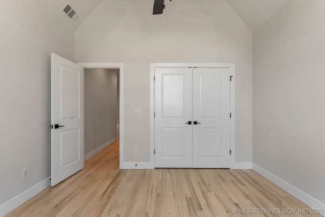 unfurnished bedroom with a closet, high vaulted ceiling, light wood-type flooring, and ceiling fan