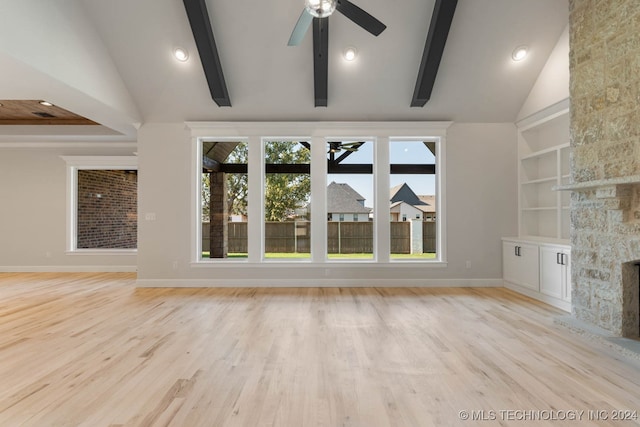 unfurnished living room featuring light hardwood / wood-style floors, a stone fireplace, beamed ceiling, high vaulted ceiling, and ceiling fan