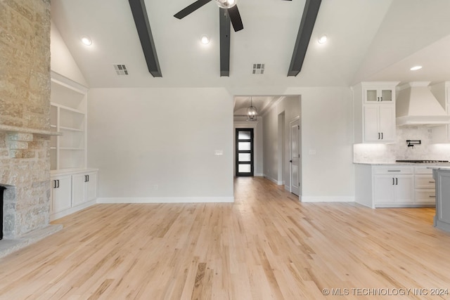 unfurnished living room featuring beam ceiling, light wood-type flooring, a fireplace, high vaulted ceiling, and ceiling fan