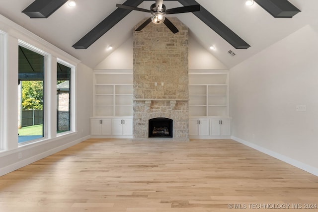 unfurnished living room with a stone fireplace, light hardwood / wood-style flooring, high vaulted ceiling, and built in features