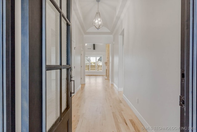 corridor with crown molding, lofted ceiling, light hardwood / wood-style flooring, and a chandelier