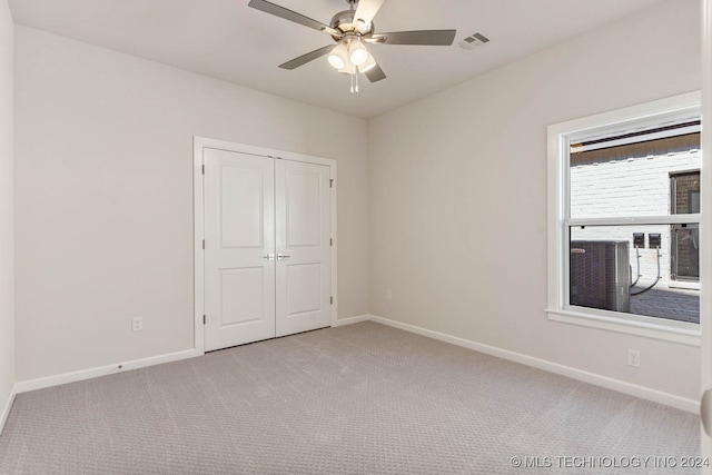 unfurnished bedroom featuring light carpet, a closet, and ceiling fan