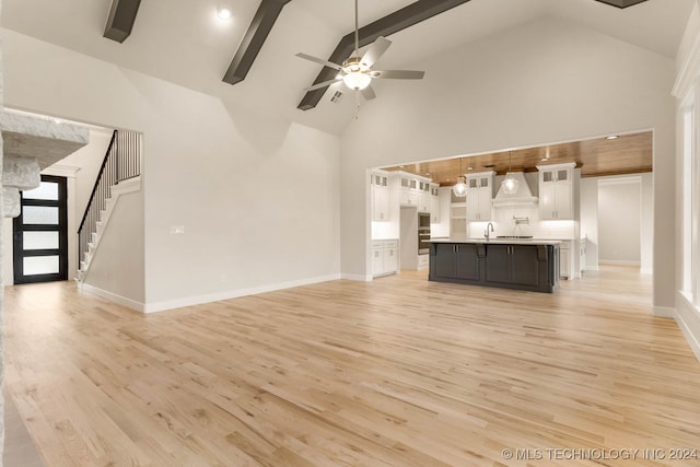 unfurnished living room featuring beam ceiling, ceiling fan, sink, high vaulted ceiling, and light wood-type flooring