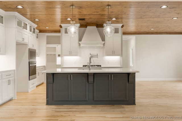 kitchen featuring white cabinets, pendant lighting, wooden ceiling, and an island with sink