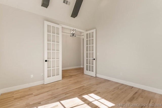 spare room with light hardwood / wood-style flooring, a notable chandelier, and french doors