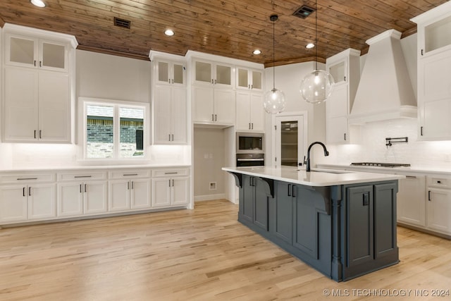 kitchen featuring wood ceiling, white cabinets, a center island with sink, and light hardwood / wood-style flooring