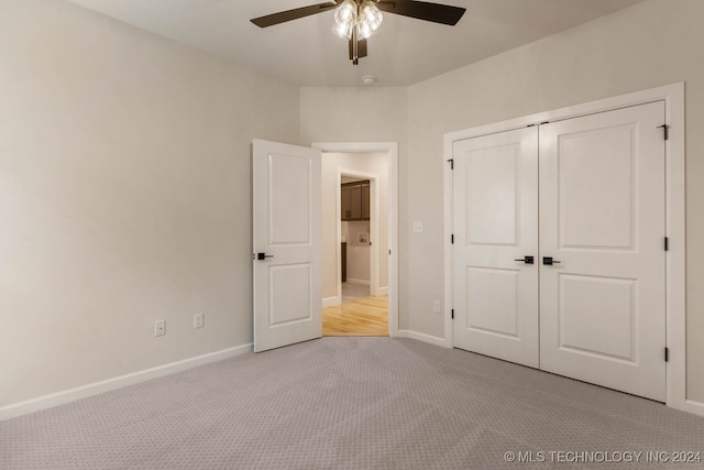 unfurnished bedroom with ceiling fan, a closet, and light carpet