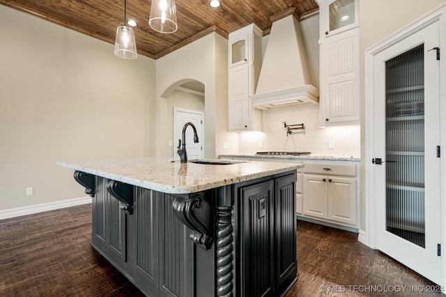 kitchen with wood ceiling, white cabinets, a center island with sink, dark hardwood / wood-style flooring, and premium range hood