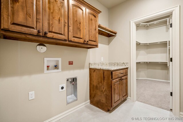 clothes washing area with washer hookup, electric dryer hookup, light colored carpet, and cabinets