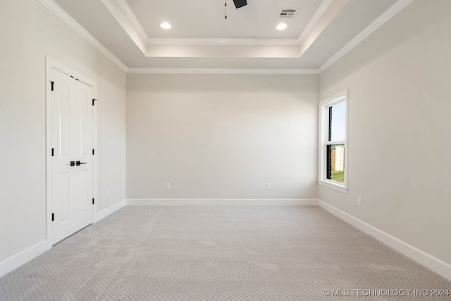 spare room with light carpet, crown molding, a tray ceiling, and ceiling fan