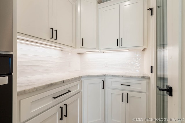 kitchen featuring oven, white cabinets, light stone counters, and backsplash