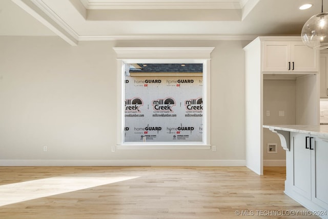 interior space with crown molding, a tray ceiling, and light wood-type flooring