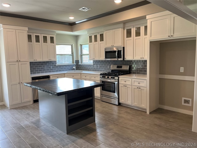 kitchen with a kitchen island, sink, stainless steel appliances, and white cabinetry