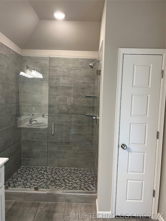 bathroom featuring walk in shower, vanity, and lofted ceiling