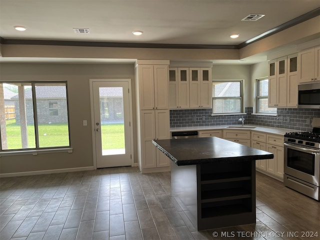 kitchen with a center island, white cabinetry, backsplash, stainless steel appliances, and sink