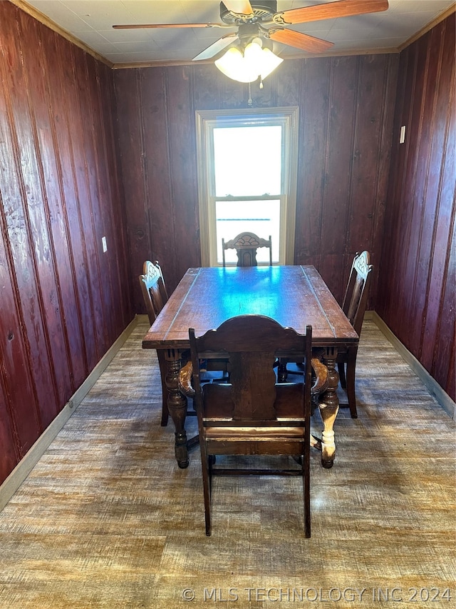 dining room with hardwood / wood-style flooring, wood walls, and ceiling fan