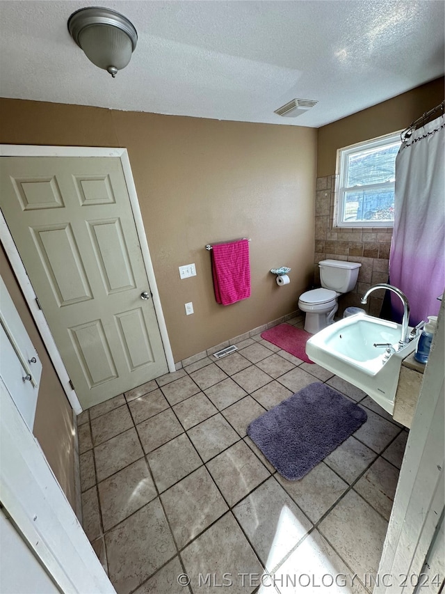 bathroom with tile flooring, toilet, and a textured ceiling