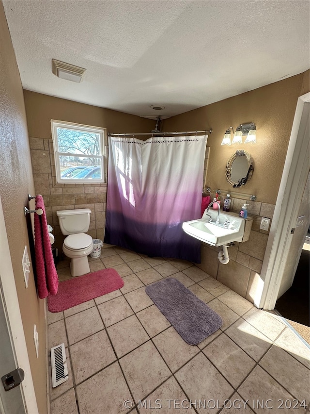 bathroom featuring toilet, tile flooring, and tile walls