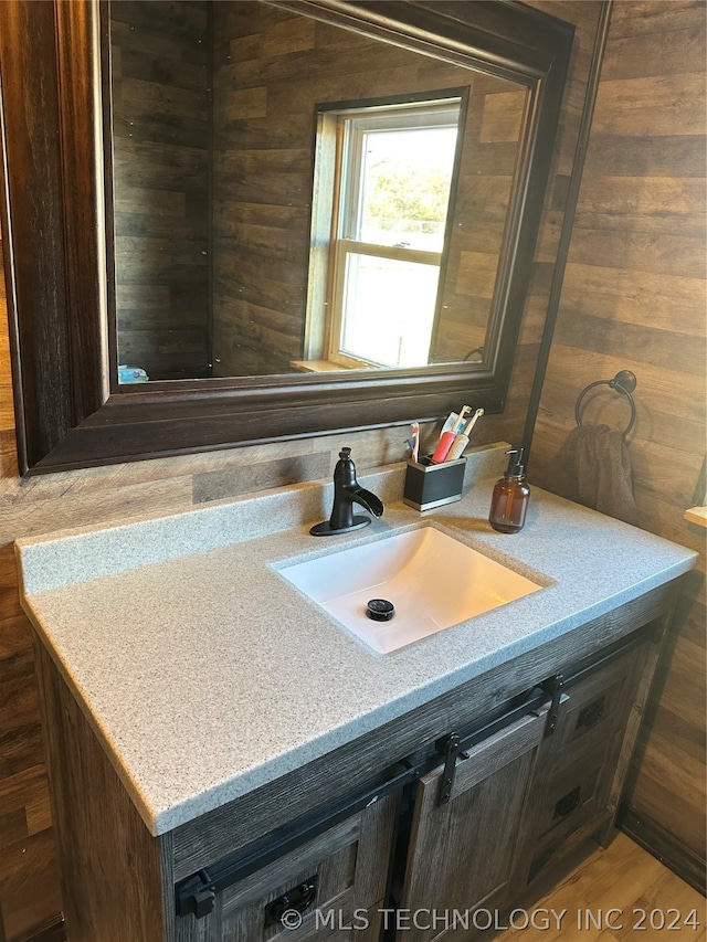 bathroom with hardwood / wood-style floors, wood walls, and vanity