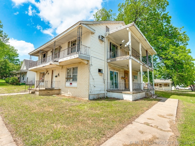 view of front of house featuring covered porch, a garage, a balcony, and a front yard