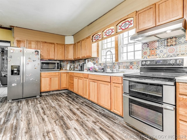 kitchen featuring light brown cabinets, sink, tasteful backsplash, hardwood / wood-style floors, and stainless steel appliances