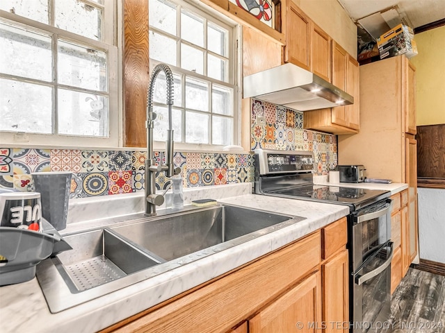 kitchen with wall chimney exhaust hood, stainless steel electric stove, dark hardwood / wood-style floors, backsplash, and sink