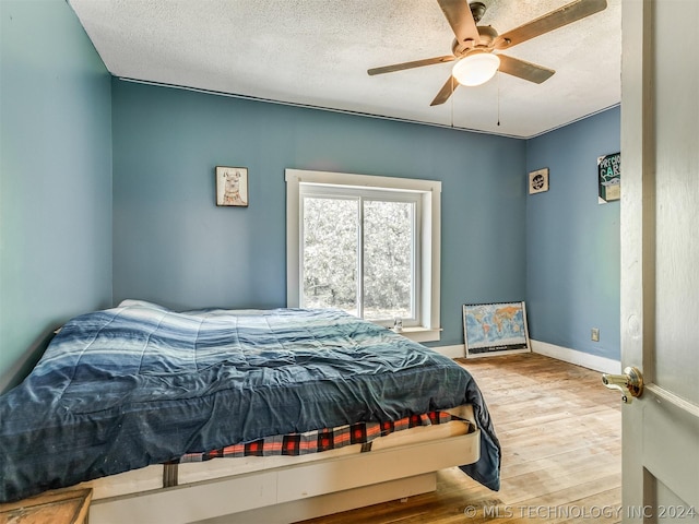 bedroom with a textured ceiling, ceiling fan, and light hardwood / wood-style floors