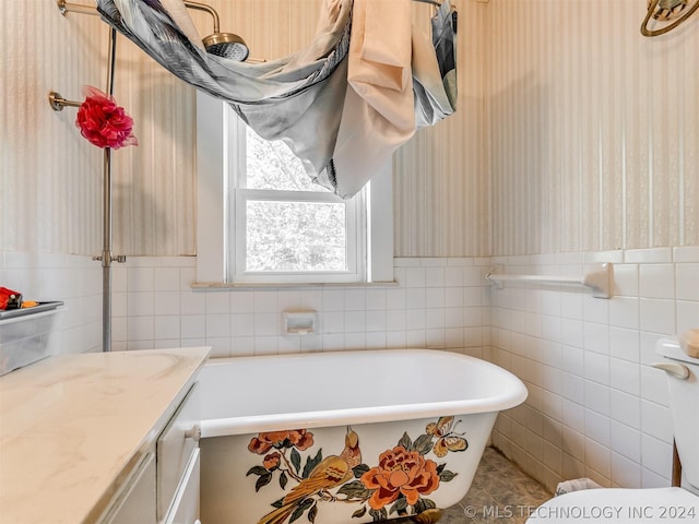 bathroom with tile walls, toilet, tile flooring, vanity, and a tub