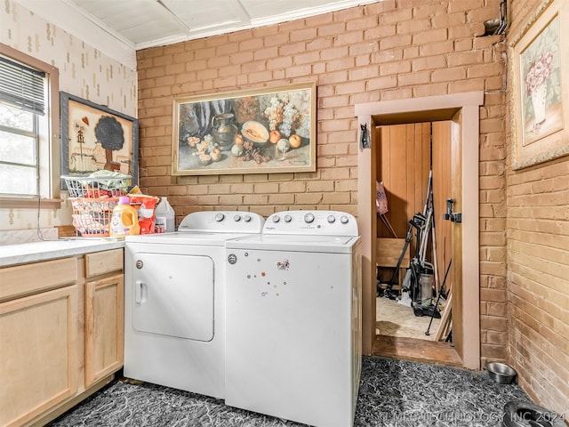 laundry room with brick wall, dark tile floors, cabinets, and washer and clothes dryer