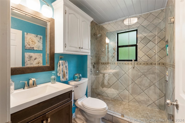 bathroom with tiled shower, vanity, and toilet