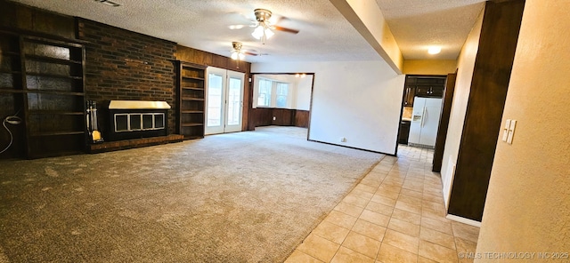 unfurnished living room with a brick fireplace, light colored carpet, a textured ceiling, and ceiling fan