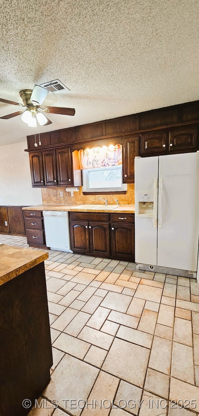 kitchen with white appliances, dark brown cabinetry, sink, and a textured ceiling