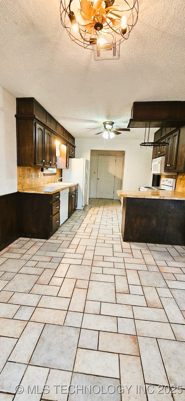 kitchen with light tile patterned flooring, white appliances, dark brown cabinets, a textured ceiling, and ceiling fan