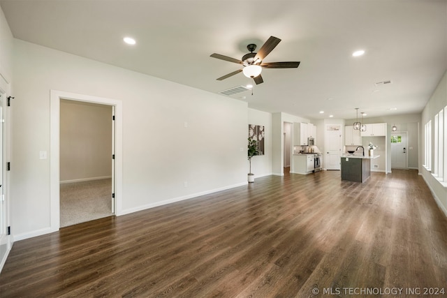 unfurnished living room with ceiling fan with notable chandelier, dark hardwood / wood-style floors, and sink