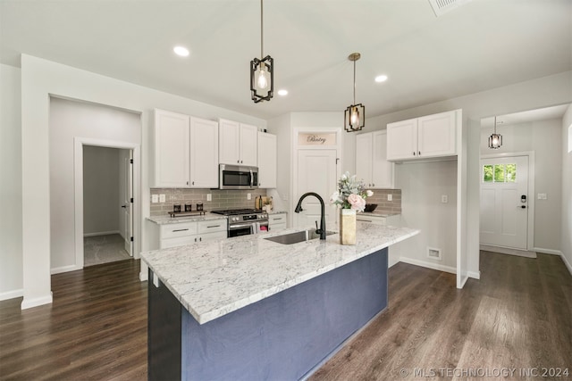 kitchen featuring appliances with stainless steel finishes, tasteful backsplash, white cabinetry, dark wood-type flooring, and a kitchen island with sink